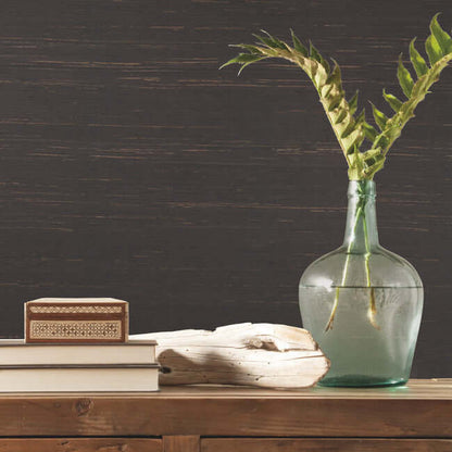 Charcoal grasscloth wallpaper with an organic woven texture and slender grass leaves. Elegant wallcovering for living rooms, bedrooms, dining rooms, offices, and statement walls.