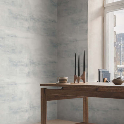 Carol Benson-Cobb Salt Flats Wallpaper in Cambrian Blue covering a modern interior wall with soft blue-gray watercolor-like texture. A serene wallpaper choice for bedrooms, living rooms, home offices, entryways, and minimalist spaces.