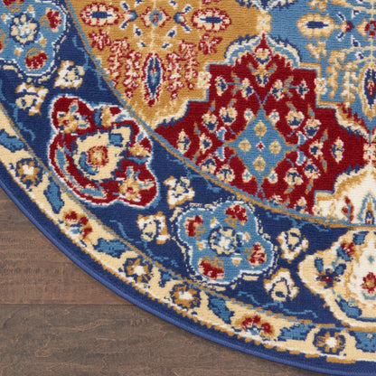 Round oriental rug with blue, gold, red and ivory floral medallion motifs on a dark wooden floor.
