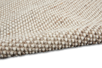 Cream and taupe boucle rug close-up with dense rounded tuft texture and soft wool-like surface.