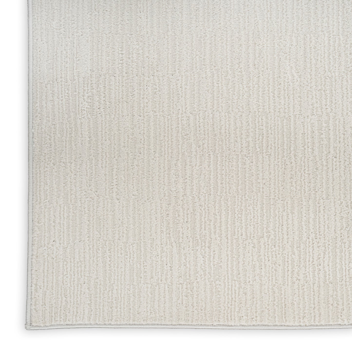 Beige rectangular rug with soft woven texture and subtle vertical rib pattern, light gray edge binding.
