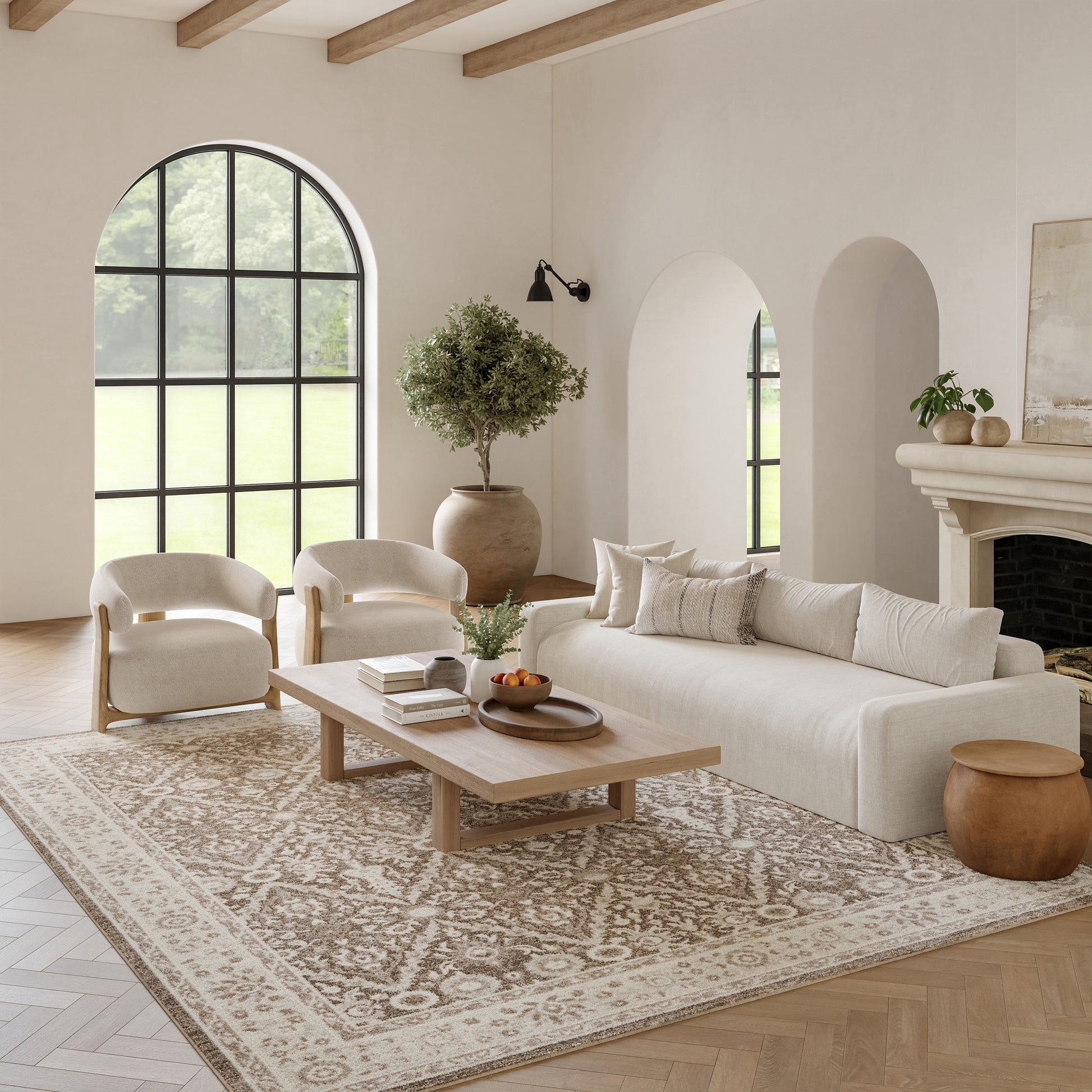 Neutral living room with arched window, cream sofa & chairs, wooden coffee table, patterned rug, potted tree, and fireplace.