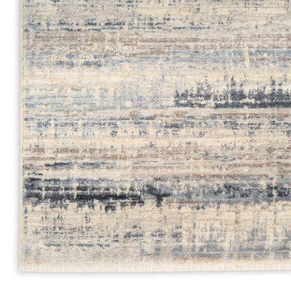Rectangular area rug with a beige base and blue-gray distressed brushstroke pattern, fringed edges.