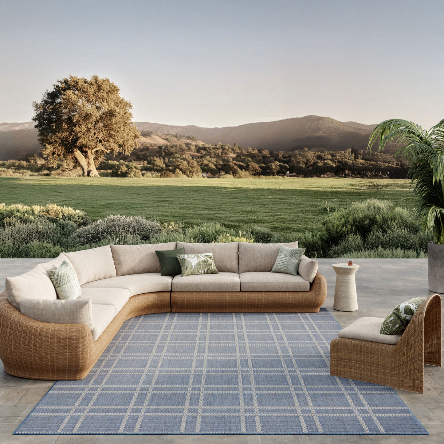 Outdoor blue plaid rug, 8' x 10', laid out on a scenic countryside patio