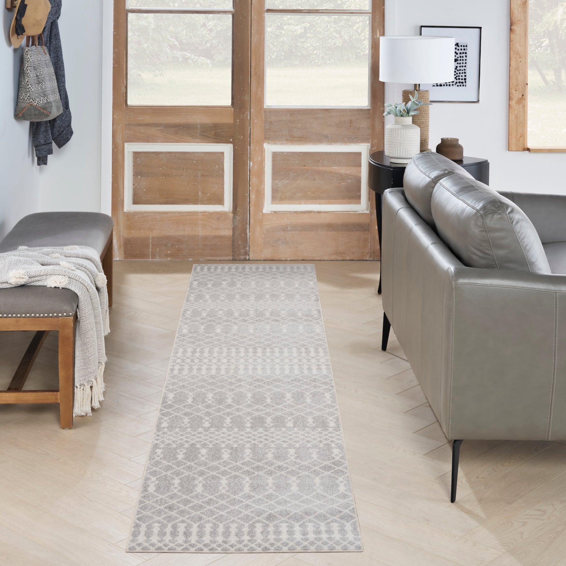 Gray geometric runner rug on a light wood floor in a modern living room with a gray sofa and bench.