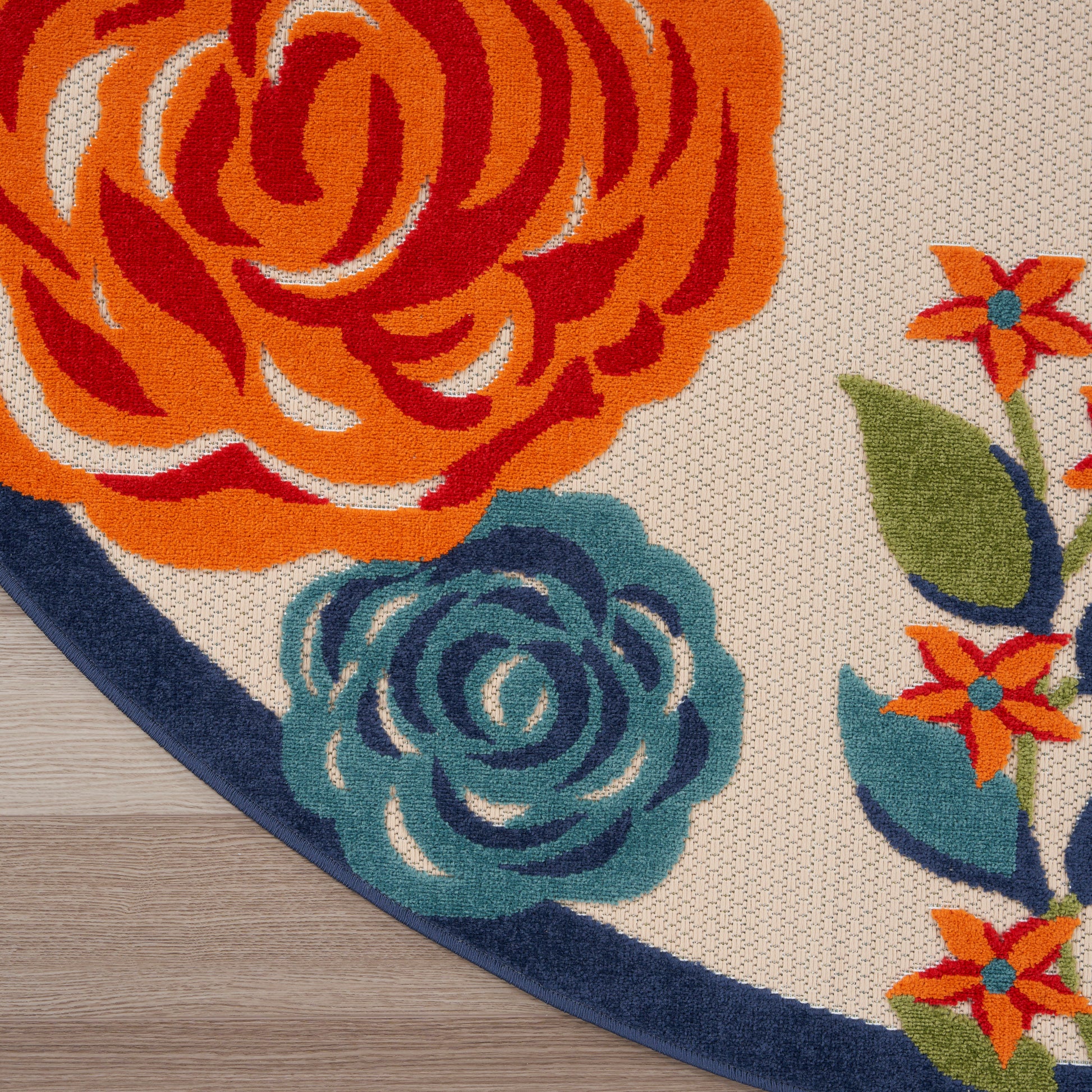 Round floral rug featuring bright orange and teal flowers on a beige woven backdrop with a navy border.