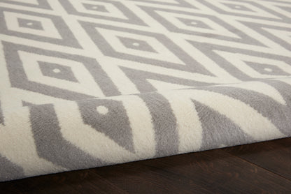 Grey and ivory geometric rug with diamond pattern, plush pile on dark hardwood floor.
