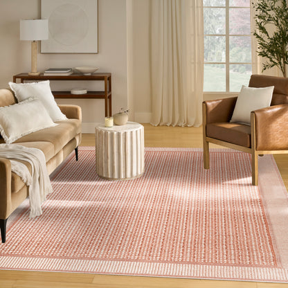 Neutral living room with beige sofa, white pillows, brown leather armchair, ribbed round side table, pink striped rug.