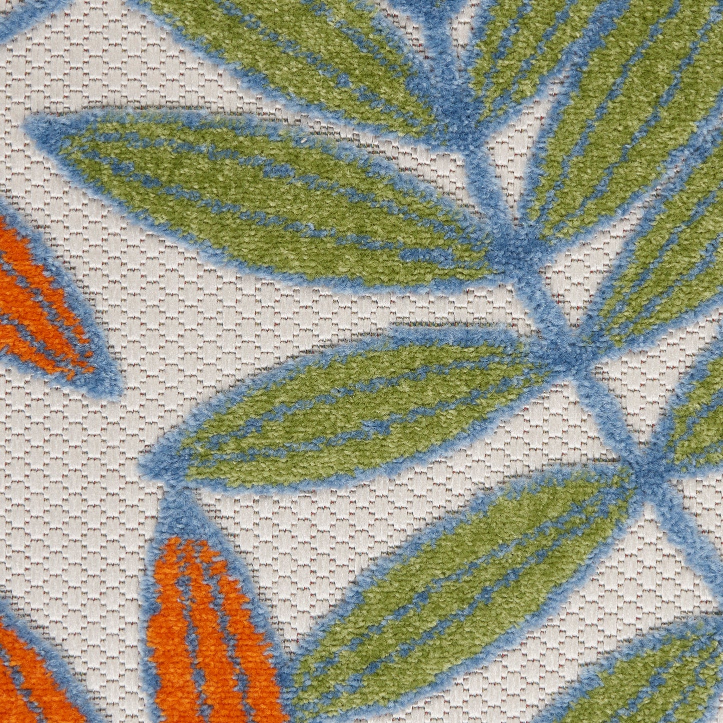 Close-up of textured fabric with blue-outlined green leaves and orange accents on a beige weave.