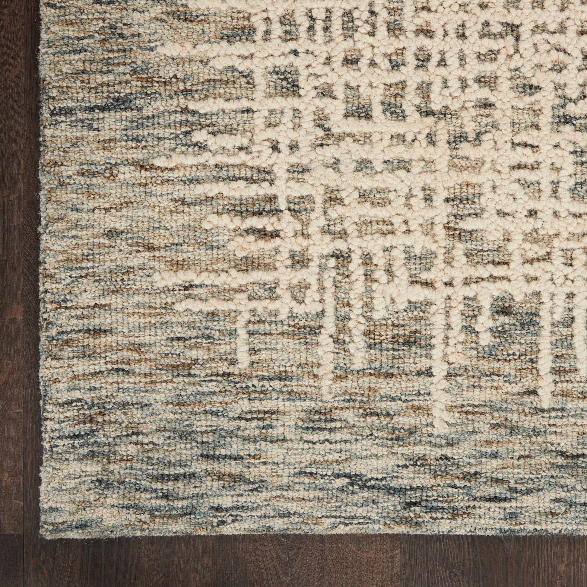 Beige and blue abstract area rug with textured loop pile on dark wood floor.