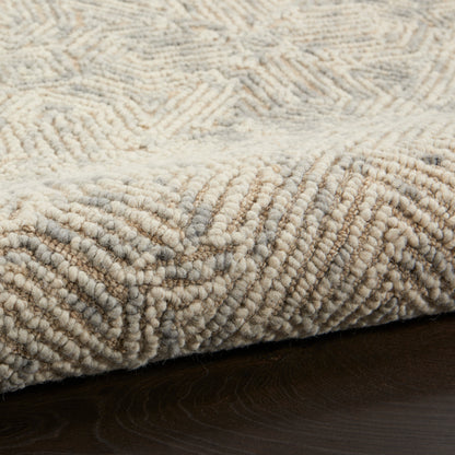 Beige plush rug with dense looped pile and subtle chevron texture on dark wood floor.