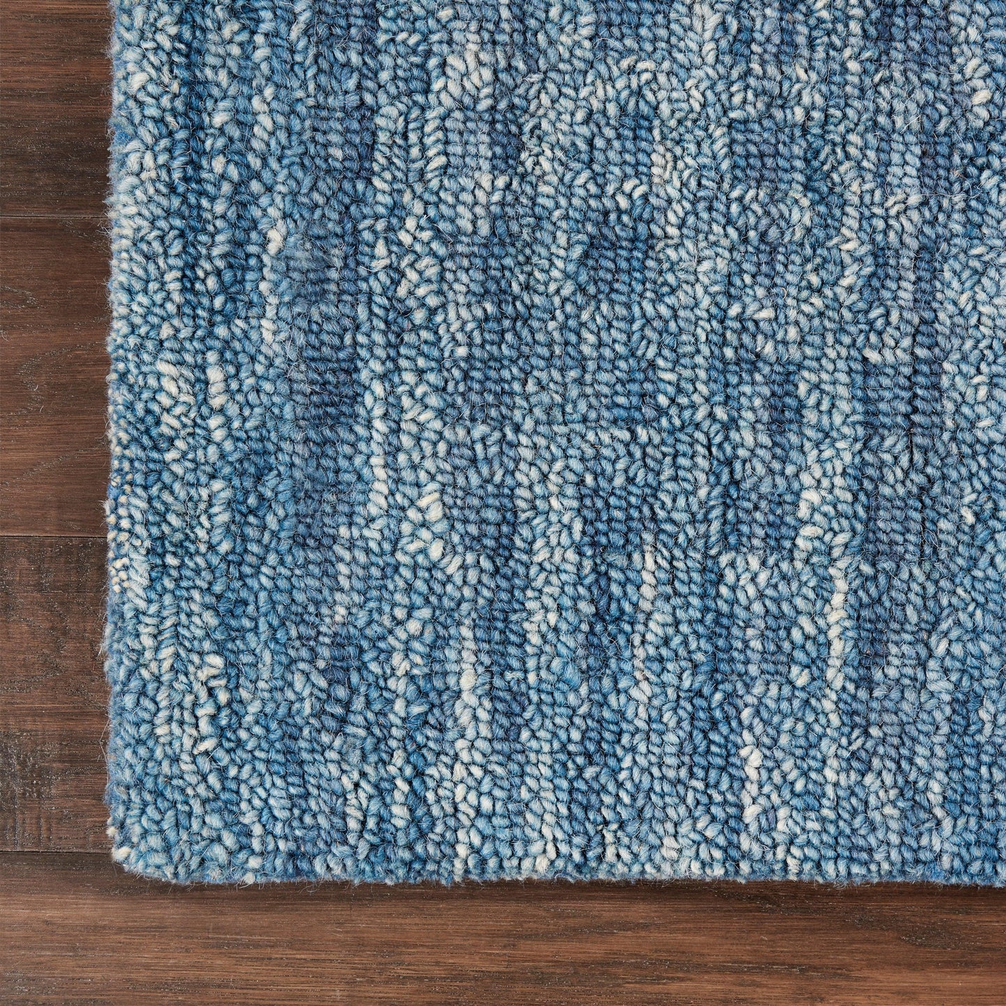 Blue variegated shag rug with looped pile in light and dark blues on a wood floor.
