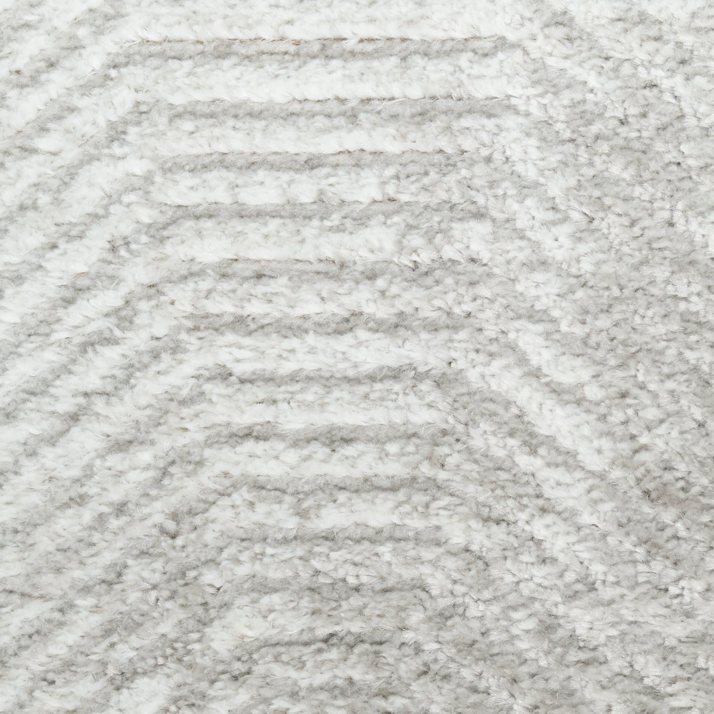 Close-up of a light gray and white plush rug with soft pile and chevron wave pattern.