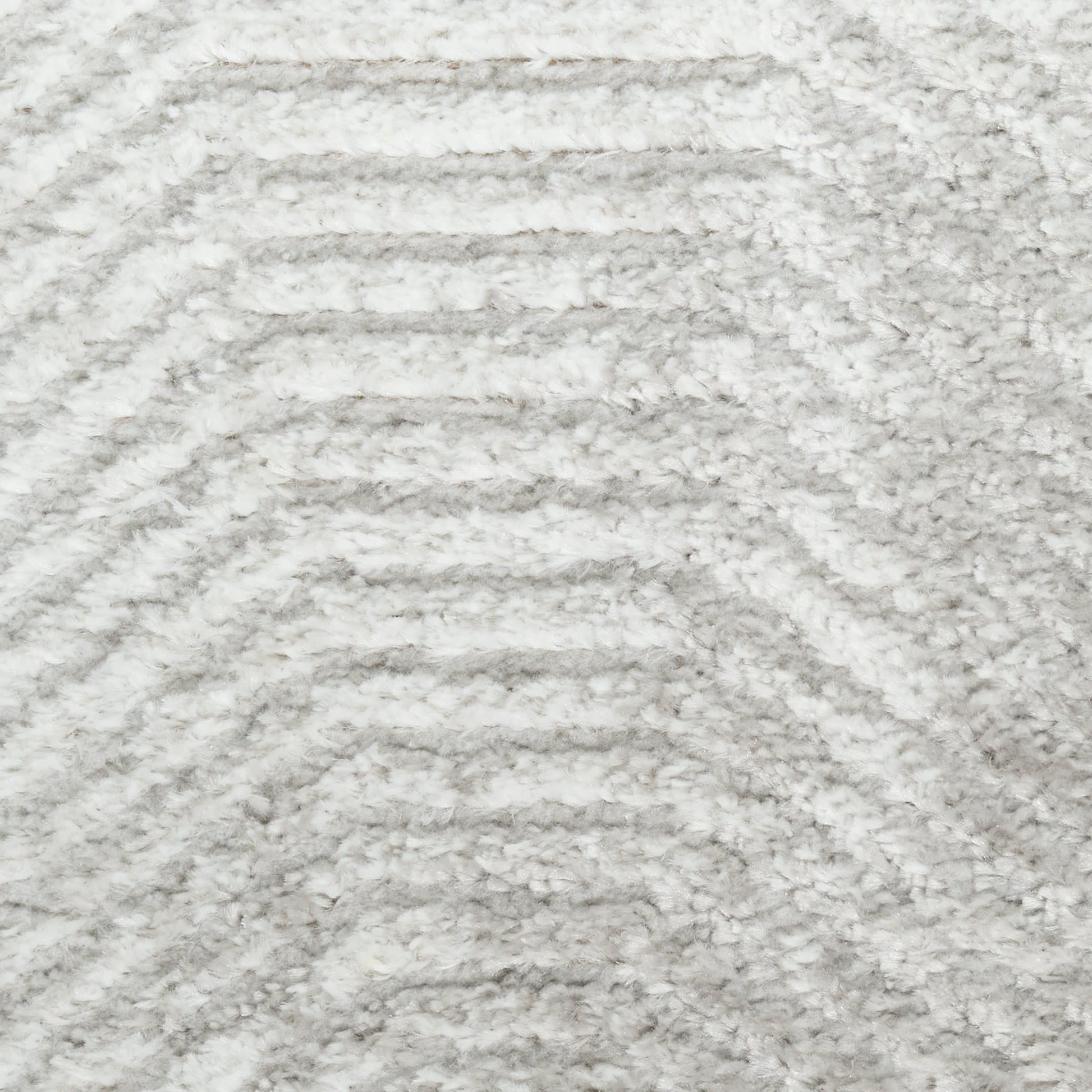 Close-up of a light gray and white plush rug with soft pile and chevron wave pattern.