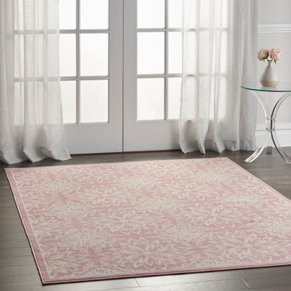 Rectangular pink area rug with white damask floral pattern in a bright room by French doors.