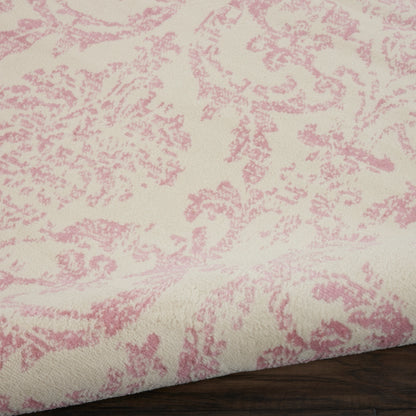 Cream fabric with pink damask floral pattern, soft woven texture, folded edge on dark wood surface.