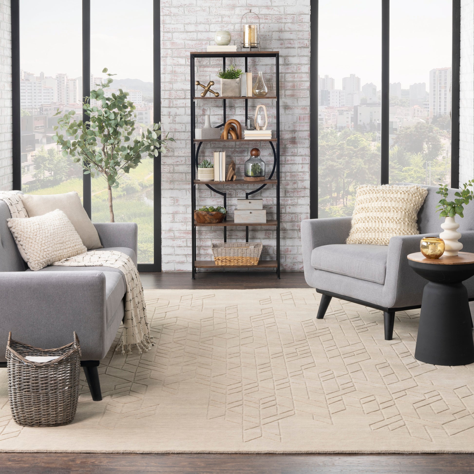 Modern living room with gray armchairs, beige geometric rug, black metal bookcase, white brick wall and large windows.