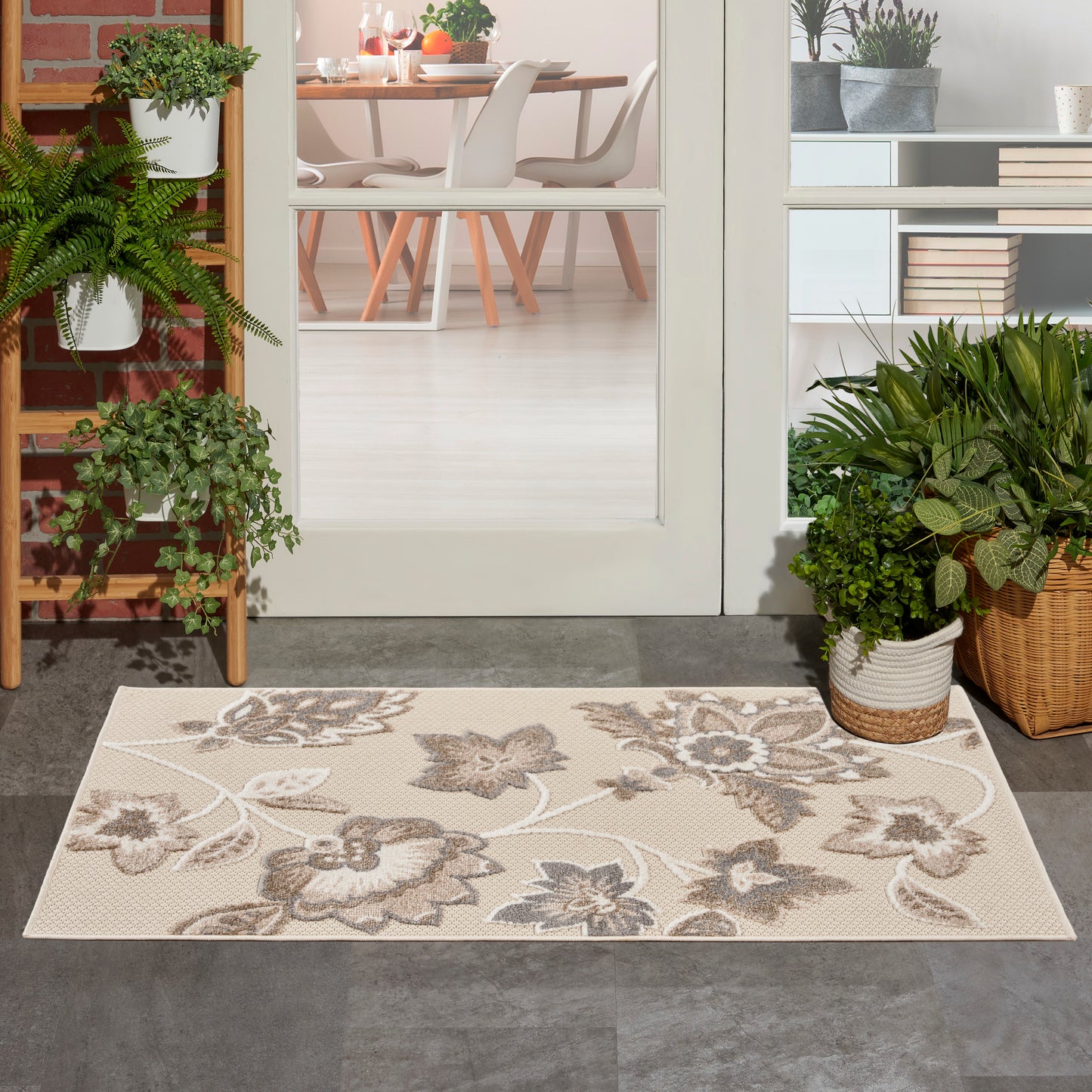 Beige floral-pattern rug with taupe leaves at a glass door; indoor-outdoor entry with potted plants.