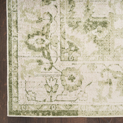 Rectangular olive and cream oriental rug with floral border on dark wood floor; fringed edge visible.