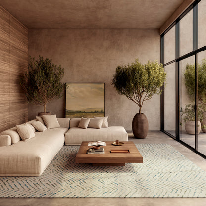 Beige L-shaped fabric sofa, cream cushions, wooden coffee table, pale chevron rug, potted trees, warm modern living room.