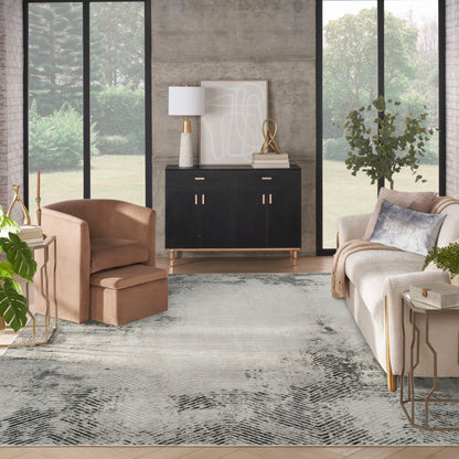 Modern living room with black sideboard, beige sofa, blush armchair, abstract art, gold accents, concrete wall, and gray rug.