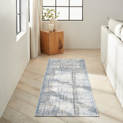 Blue-gray distressed rectangular runner rug on light wood floor beside beige sofa, wooden cube side table with vases.