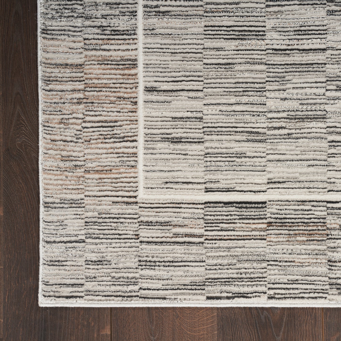Rectangular neutral-toned rug with striped patchwork in beige, gray & taupe on dark wood floor.