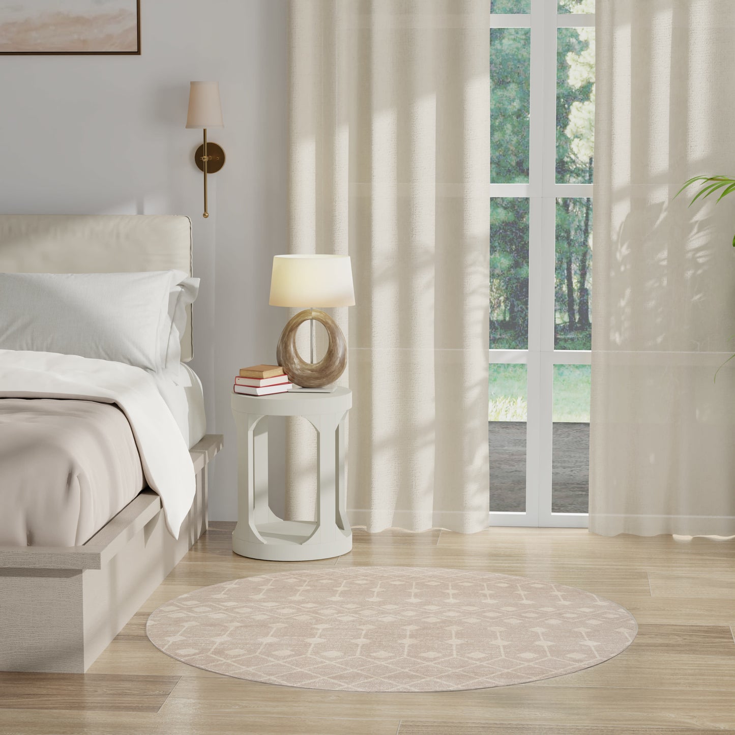 Neutral bedroom with cream bedding, round white side table, glass lamp, stack of books, beige circular rug, sheer curtains.