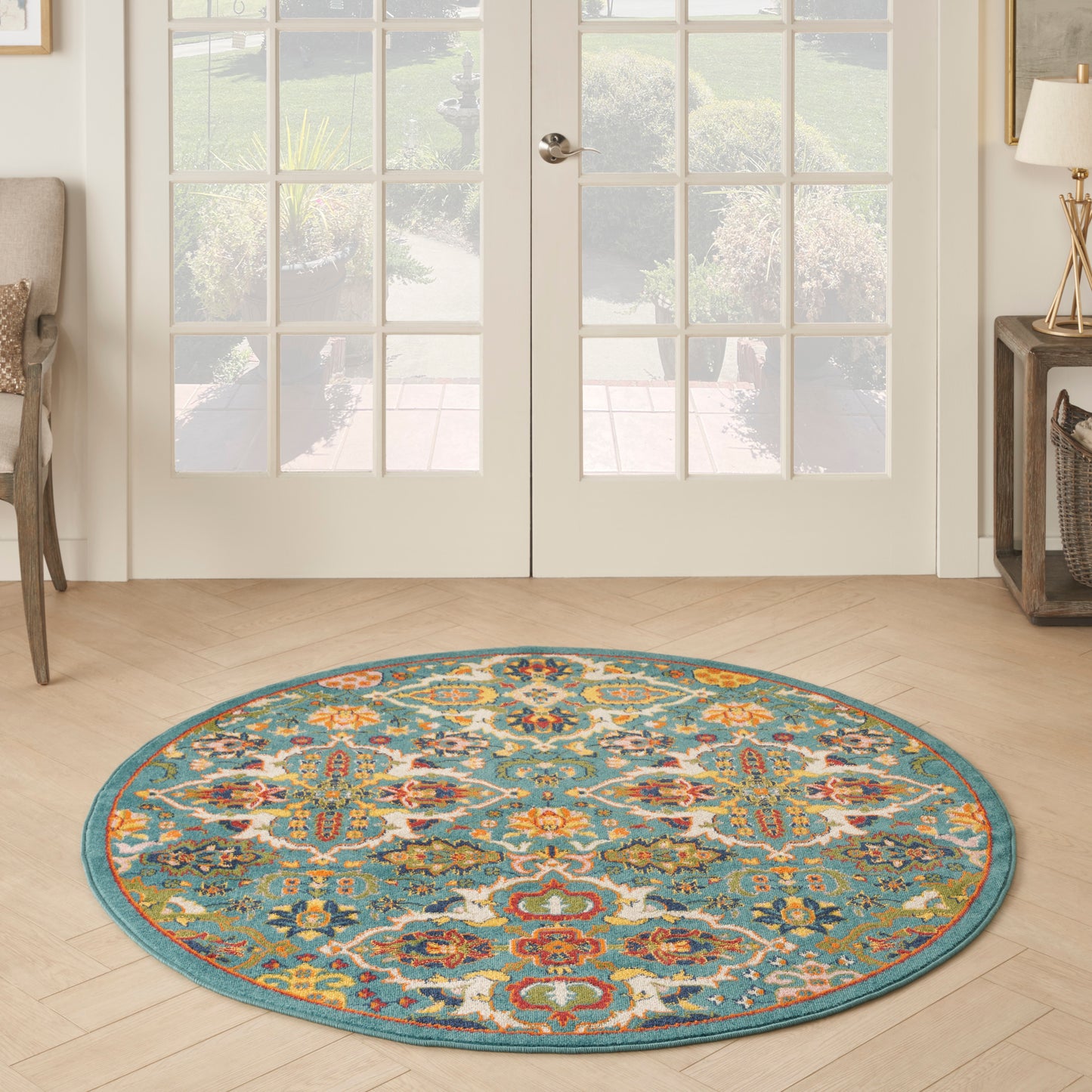 Round teal boho rug with vibrant multicolor floral motif on light wood entryway floor.