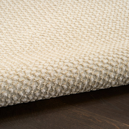 Cream textured loop-pile rug on dark wood floor; beige fibers, cozy modern living-room accent.