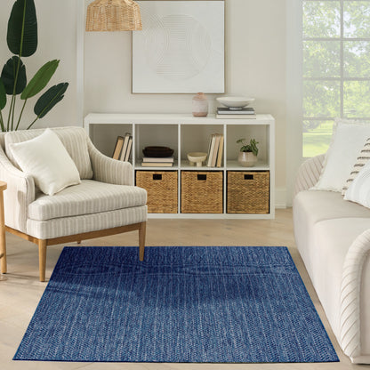 Cozy living room with a rectangular blue woven rug, cream sofa and armchair, white cubby shelf with wicker baskets.