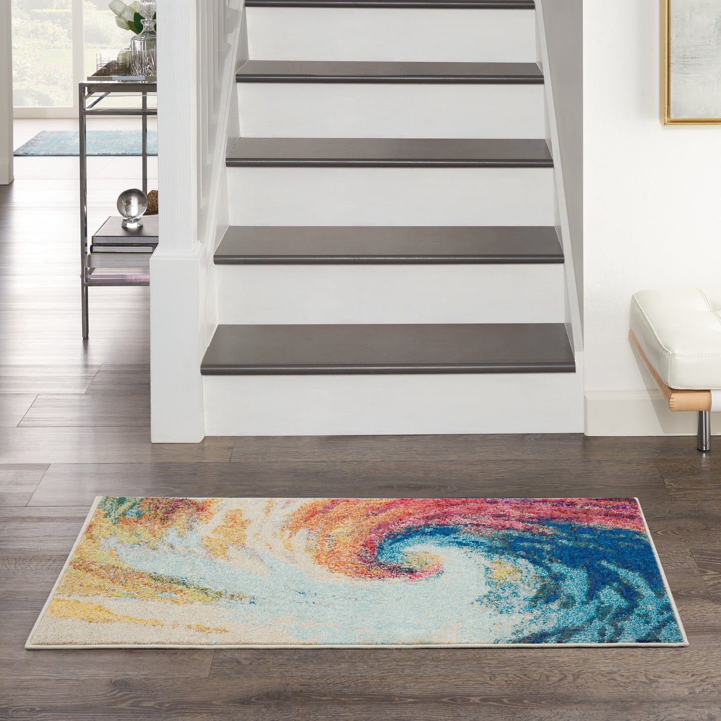 Rectangular area rug with vibrant abstract swirl in orange, yellow, blue and teal, in a modern foyer by the staircase.