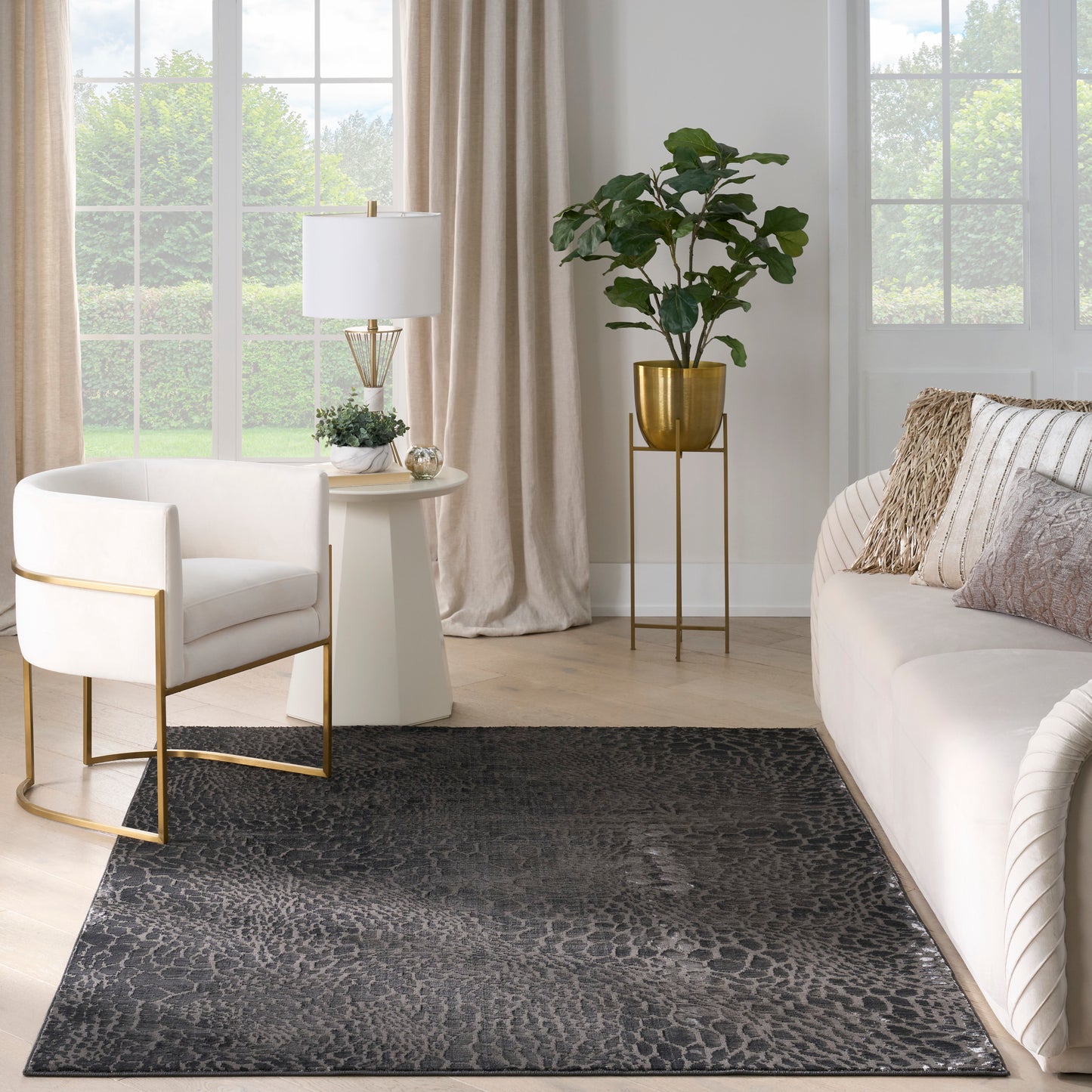 Contemporary living room with dark animal-pattern rug, white sofa and chair with gold frames, beige curtains, brass accents.