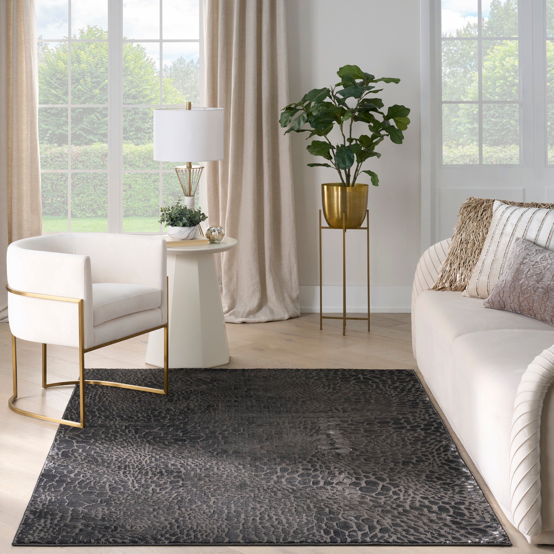 Contemporary living room with dark animal-pattern rug, white sofa and chair with gold frames, beige curtains, brass accents.