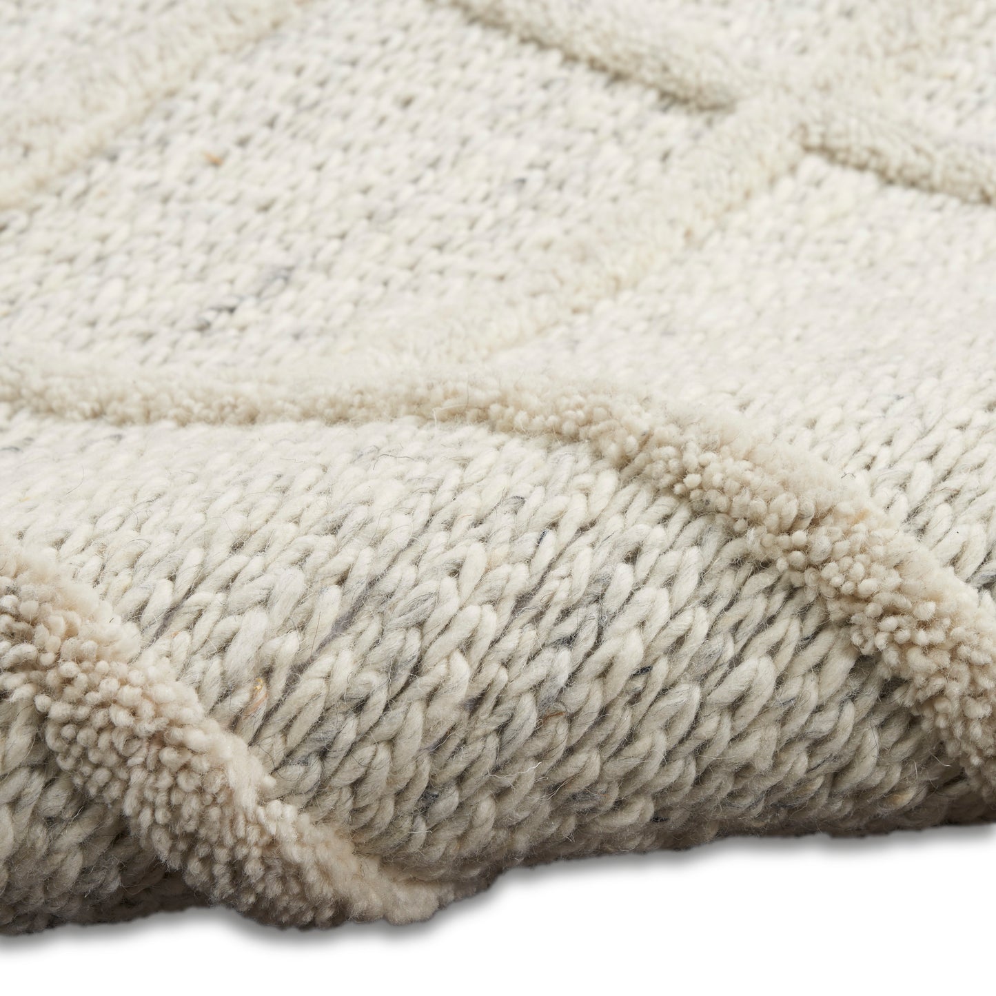 Cream chunky knit rug with thick boucle yarn, braided texture and plush, cozy surface.