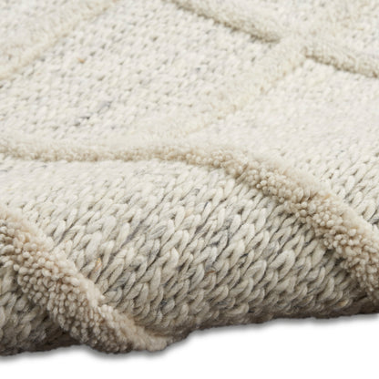 Cream chunky knit rug with thick boucle yarn, braided texture and plush, cozy surface.
