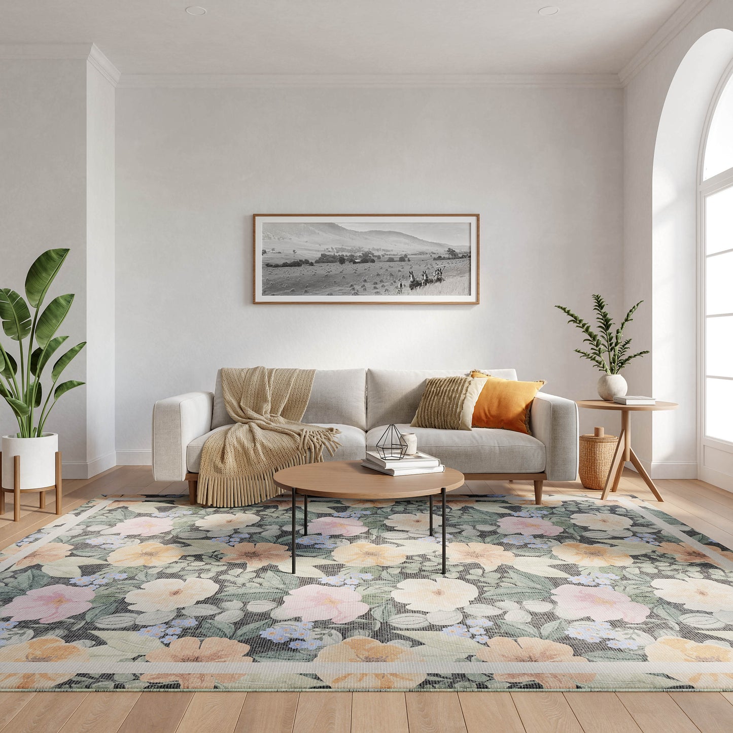 Light gray sofa with beige throw and orange pillow, round wooden coffee table on a pastel floral rug with potted plants.