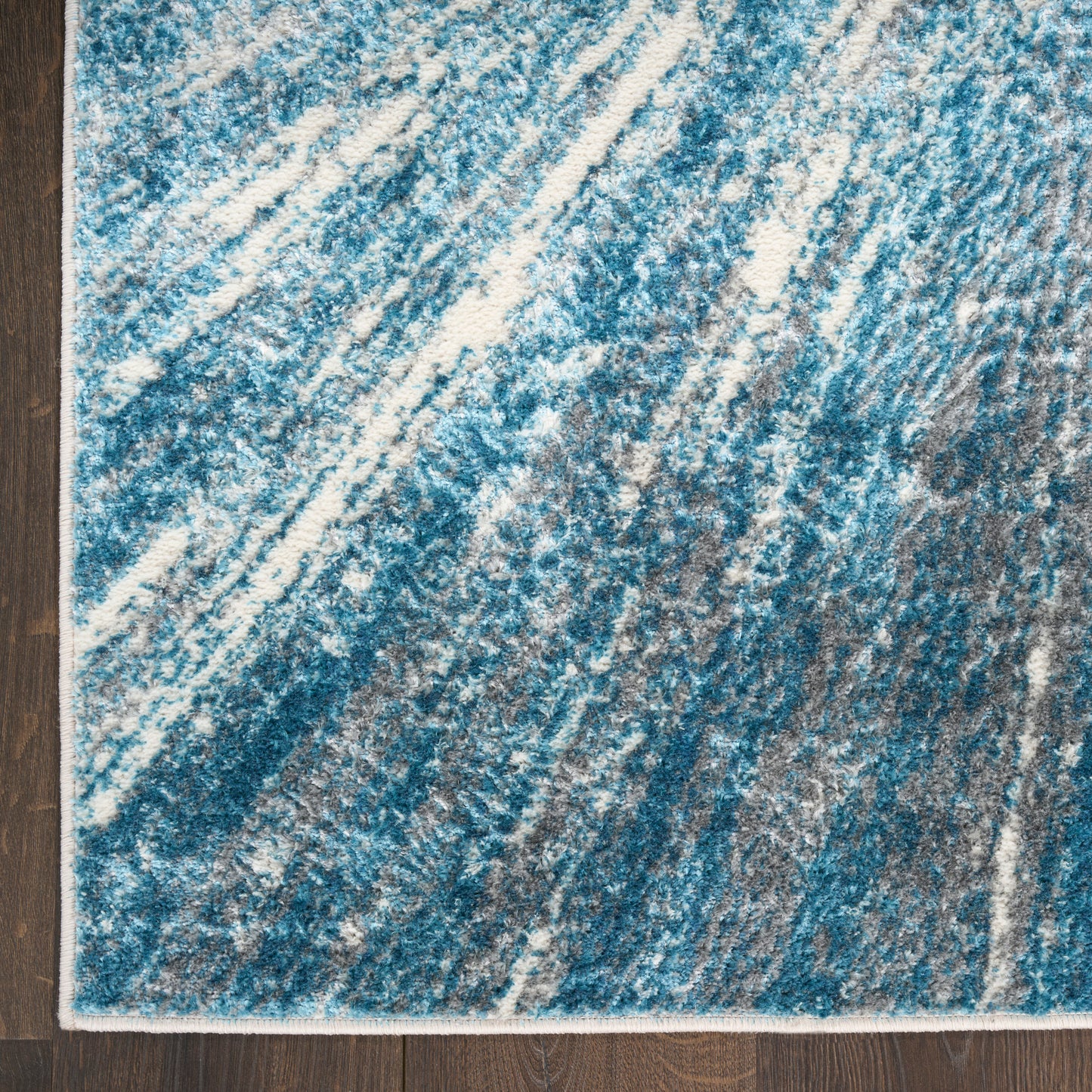Blue & white abstract rectangular area rug with diagonal streaks on dark wood floor.