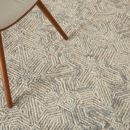 Beige textured loop-pile rug with geometric square pattern; wooden chair leg rests nearby.