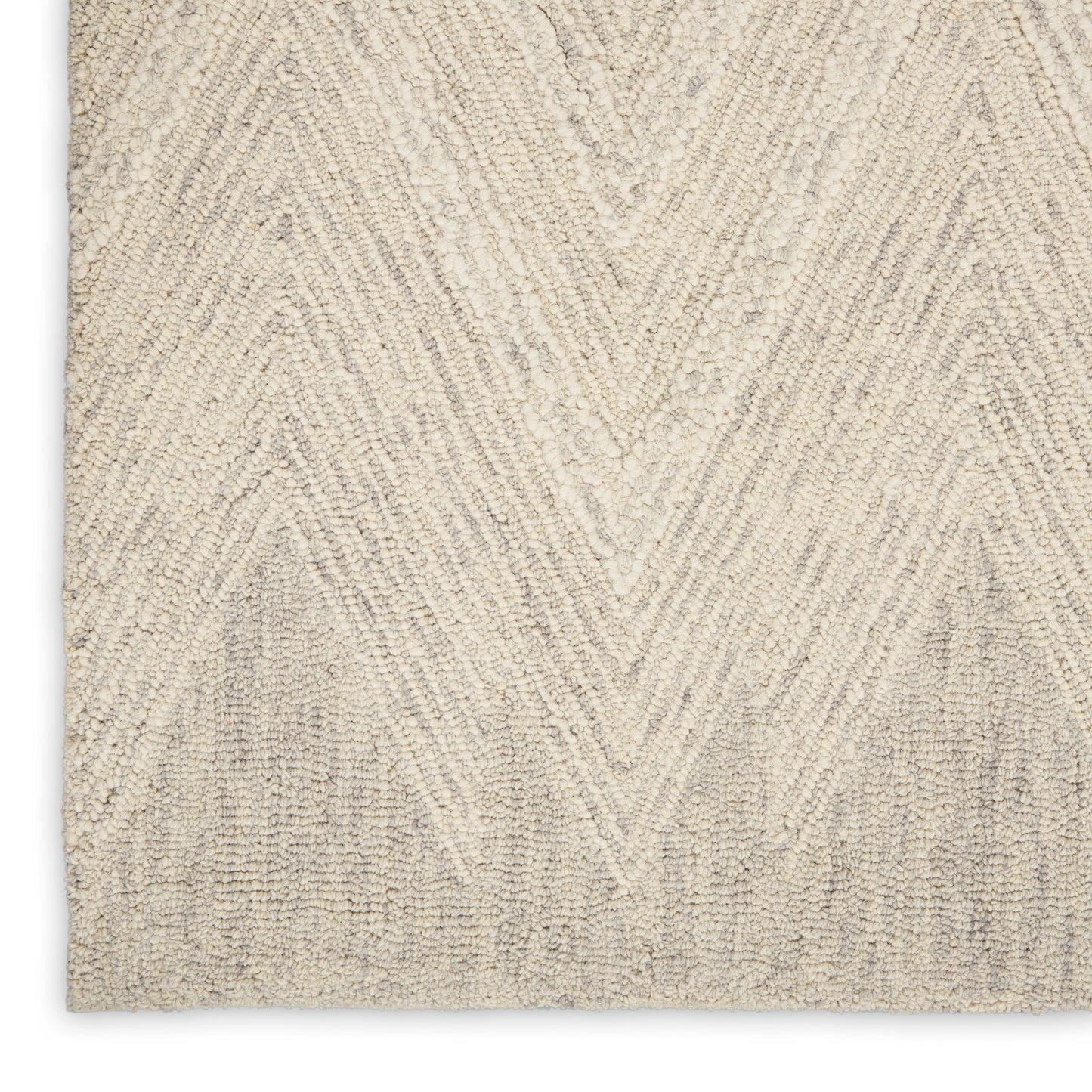 Beige rug close-up with cream chevron zigzag pattern in a tufted textured pile.