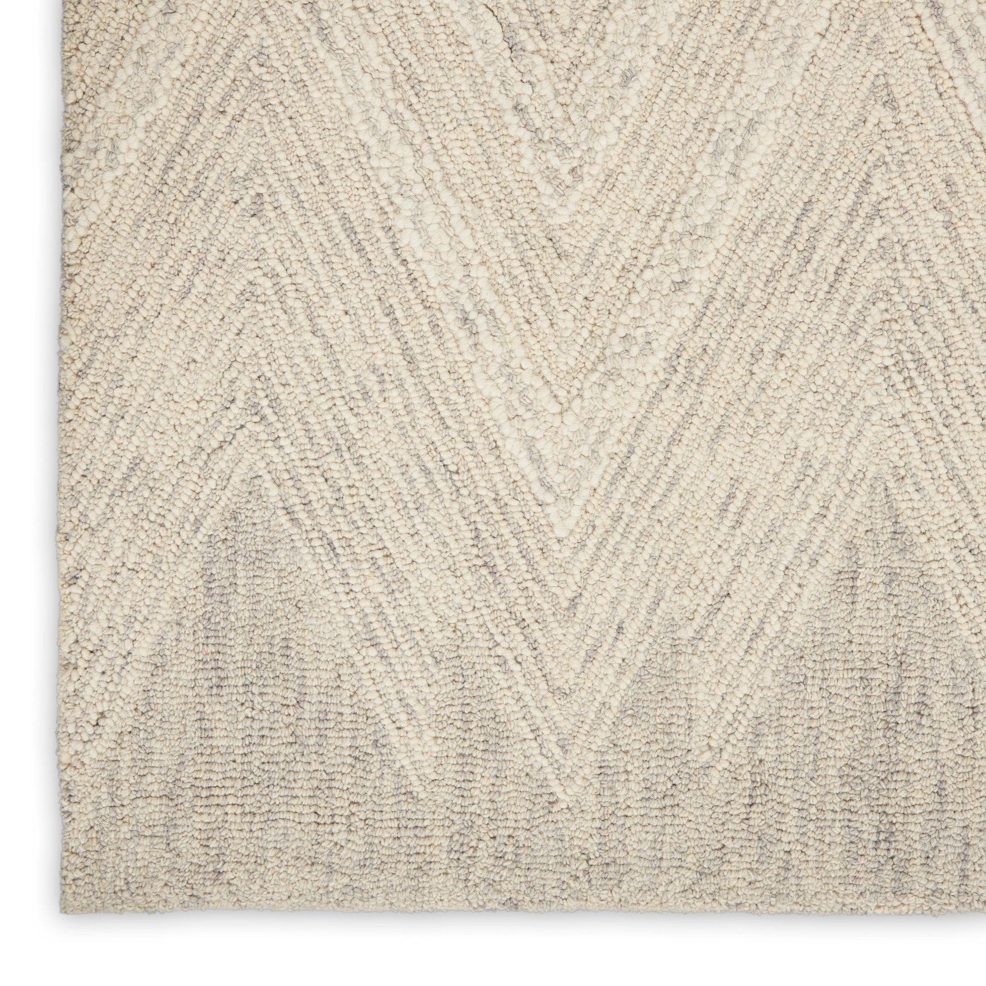 Beige rug close-up with cream chevron zigzag pattern in a tufted textured pile.