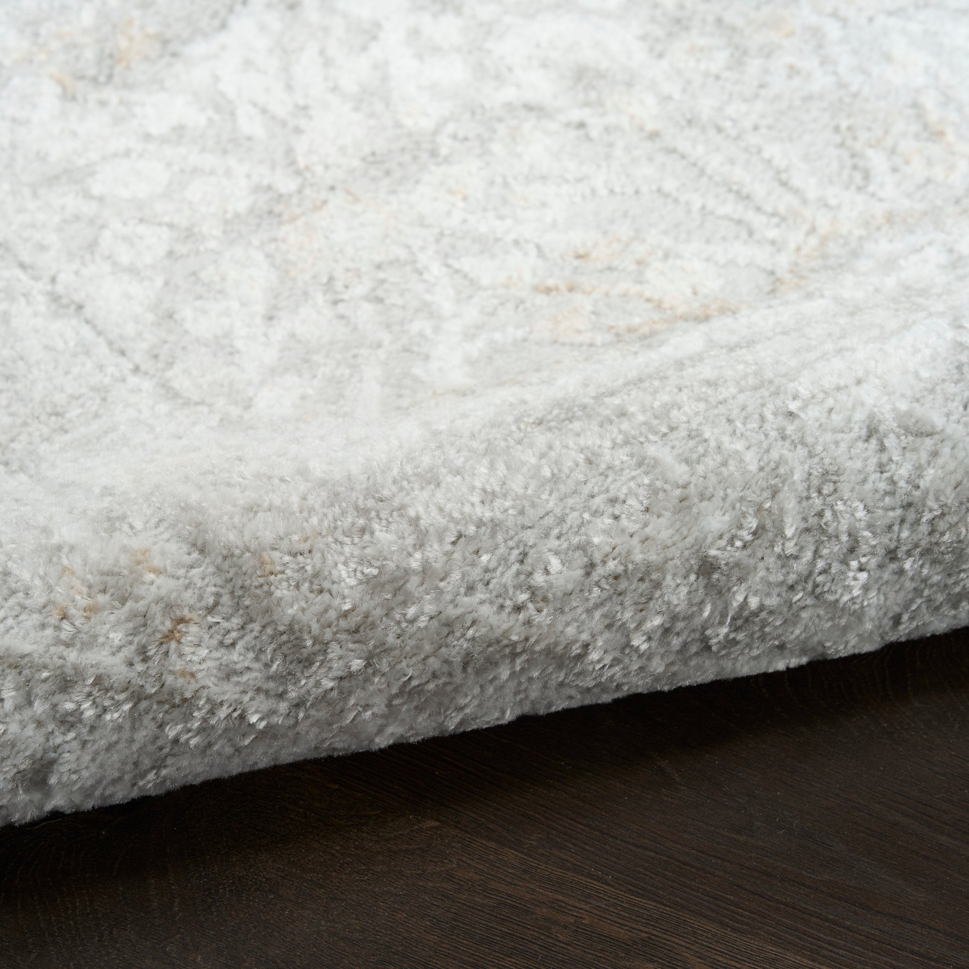 Soft gray shag rug with plush pile on dark wood floor.