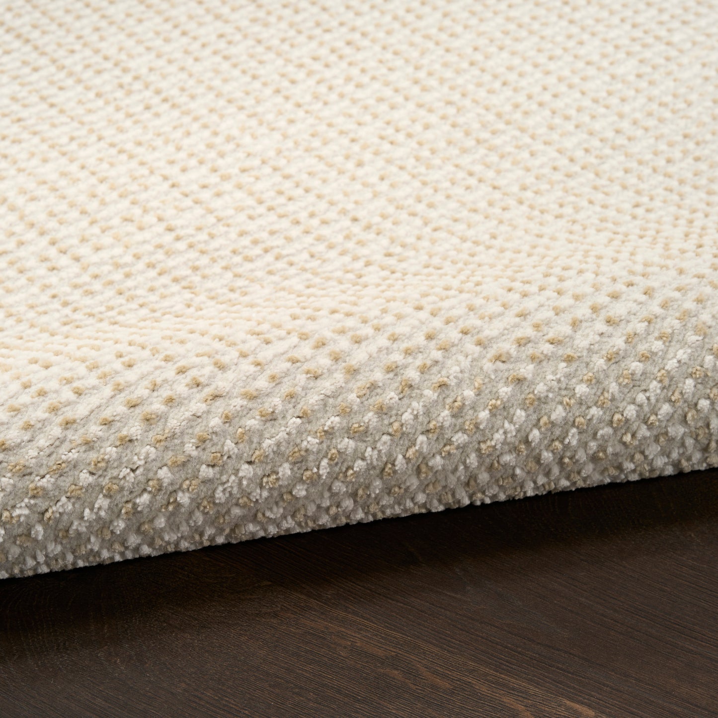 Cream textured rug with a dotted loop pattern on dark wood floor.