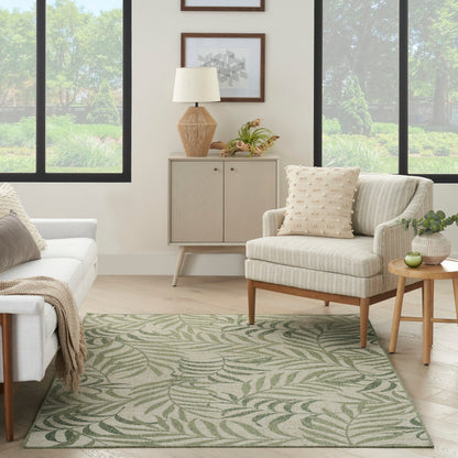 Neutral living room with palm-leaf rug, beige striped armchair, light sofa, mid-century wood furniture, greenery.
