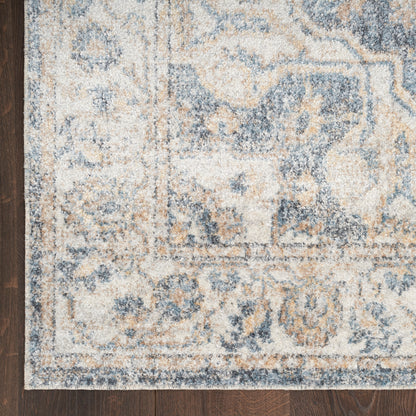 Distressed blue and beige area rug with ivory border on dark wood floor.