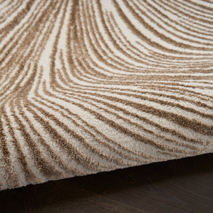 Close-up of a beige-brown zebra-striped shag rug with a textured pile on dark hardwood floor.