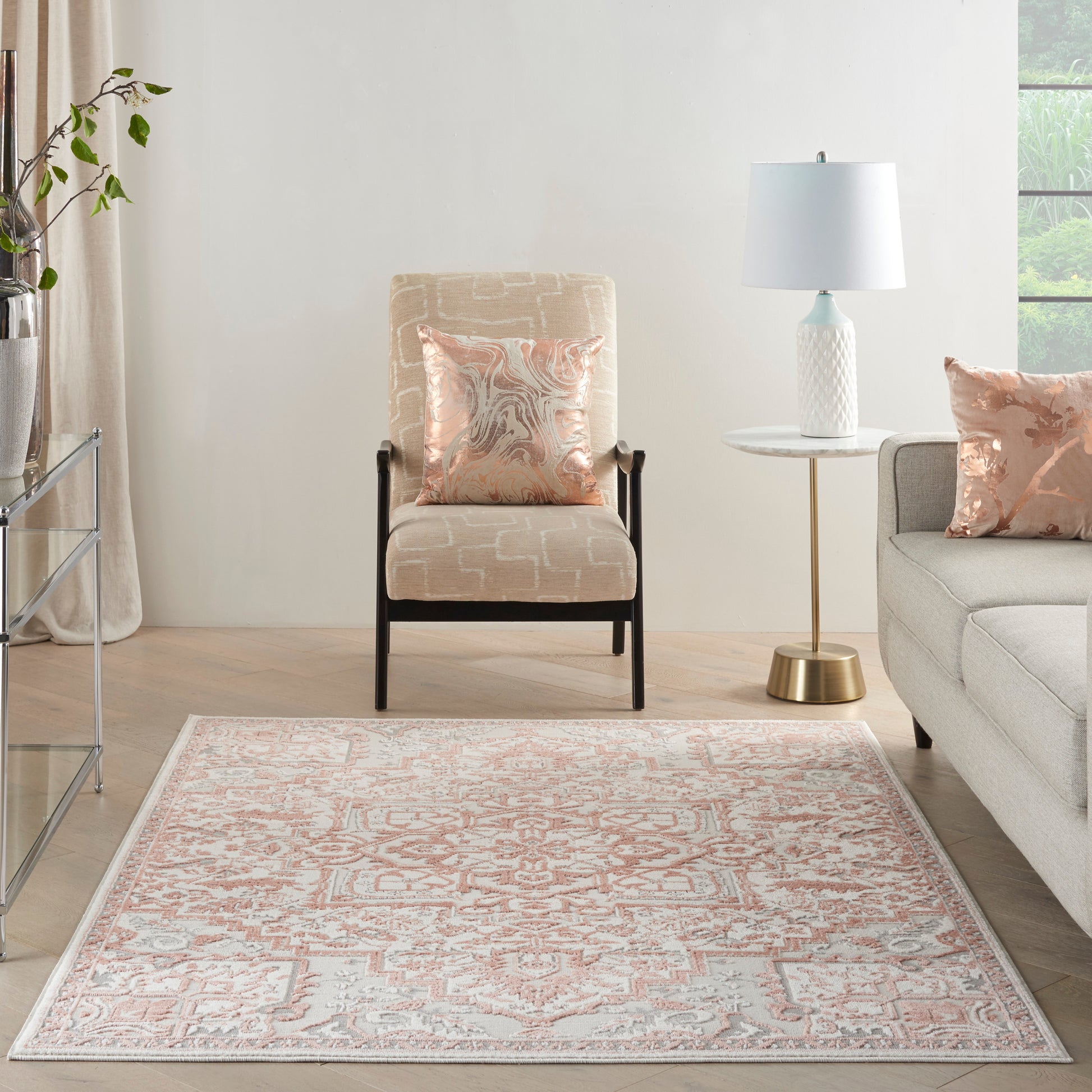 Peach-and-ivory patterned area rug in a light living room with beige armchair, round white side table, and pastel cushions.