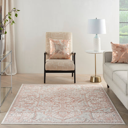 Peach-and-ivory patterned area rug in a light living room with beige armchair, round white side table, and pastel cushions.