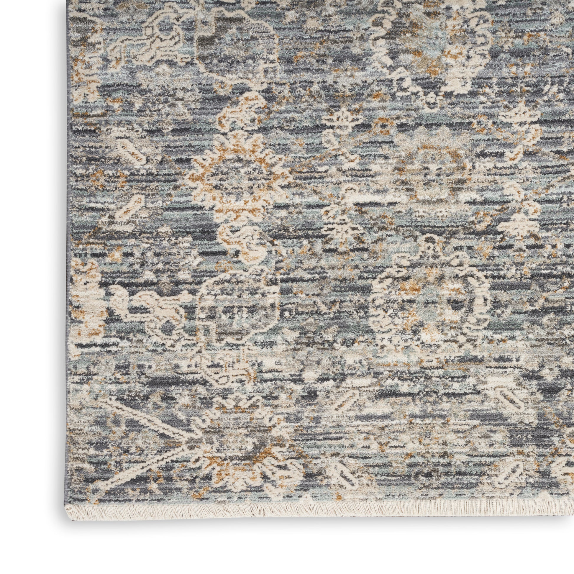 Distressed blue-gray area rug with ivory floral medallion pattern and fringed edges.