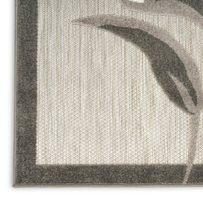 Beige woven rug close-up with dark border & abstract leaf pattern.